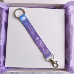 Llavero solidario Fundación Síndrome de Dravet en caja de regalo blanca con papel morado idea de regalo solidario